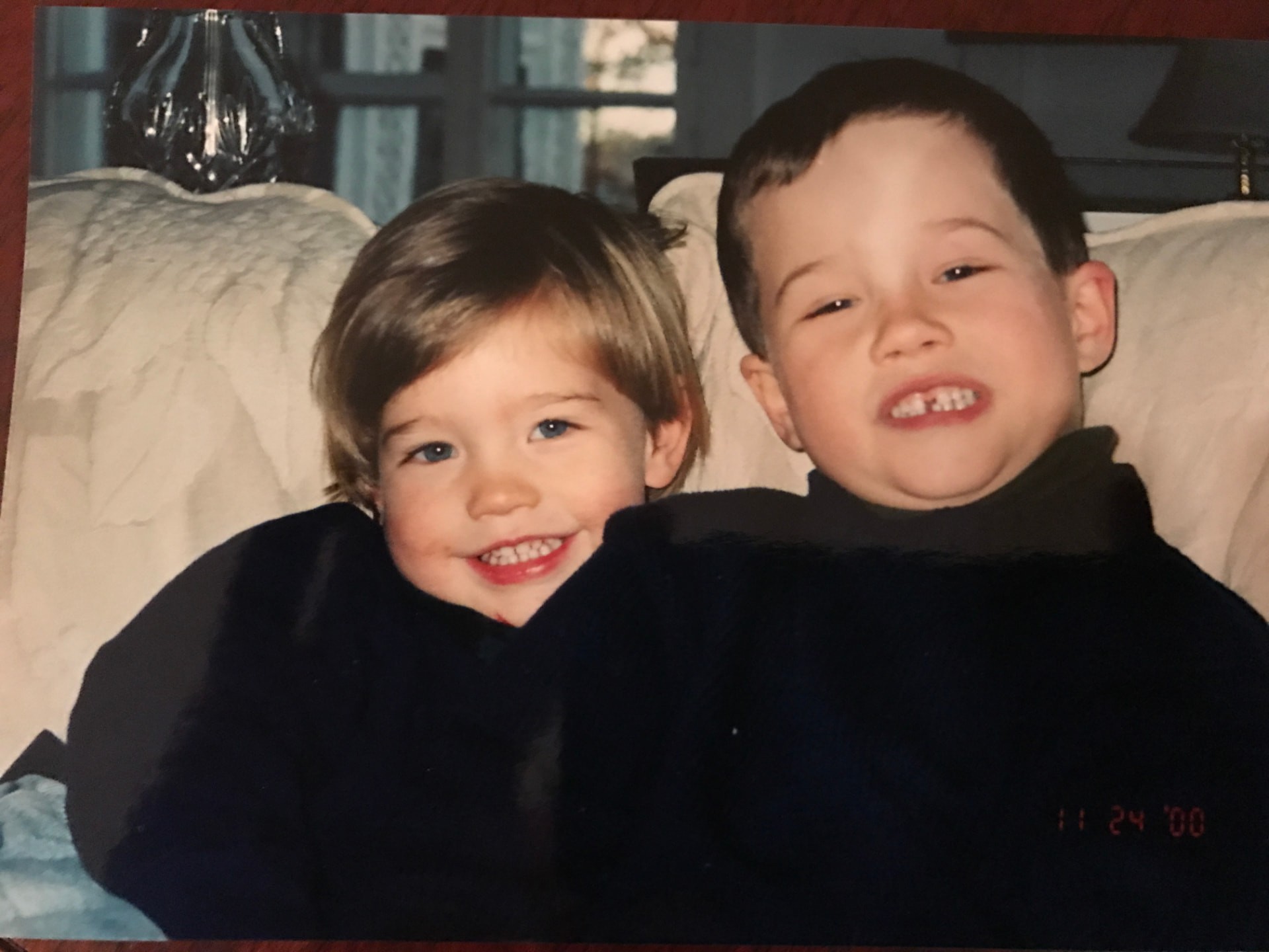 John and Scott as little boys in navy sweaters, leaning together on a couch