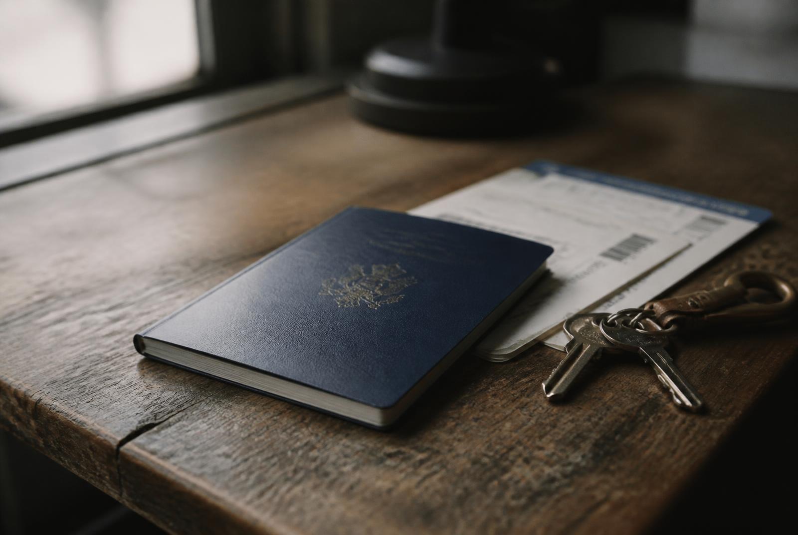 A newly renewed passport on a wooden table beside a boarding pass and a set of keys