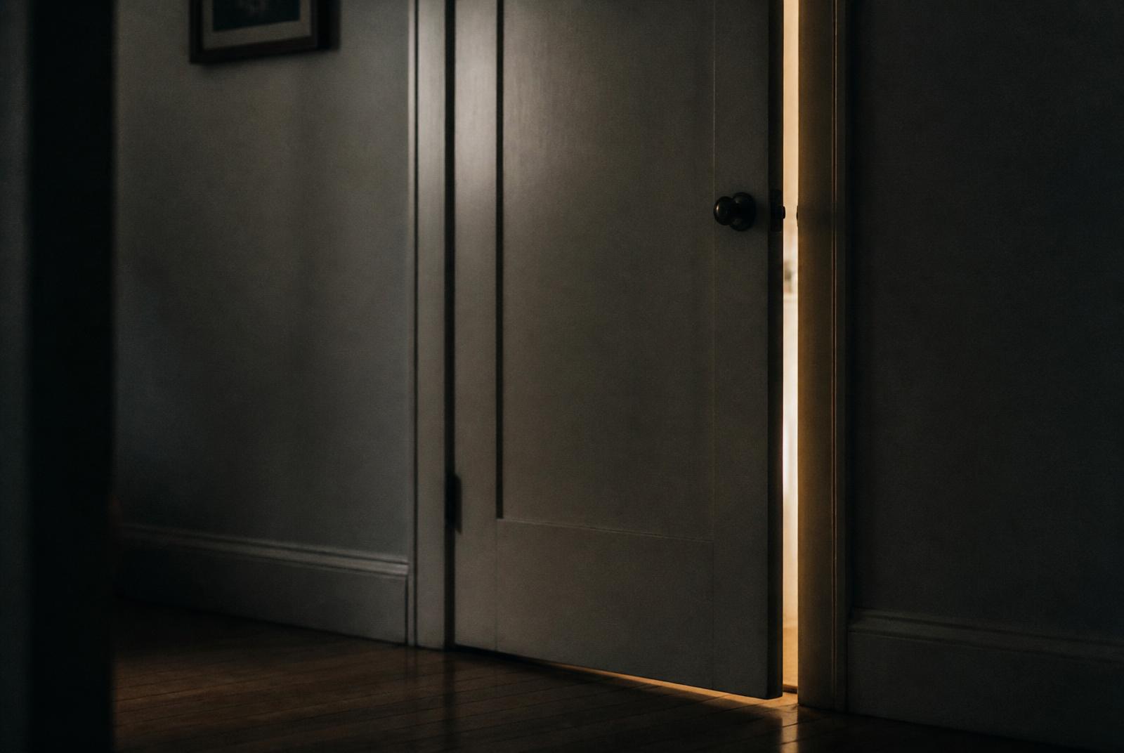 A door being closed, a narrow band of warm light in the gap