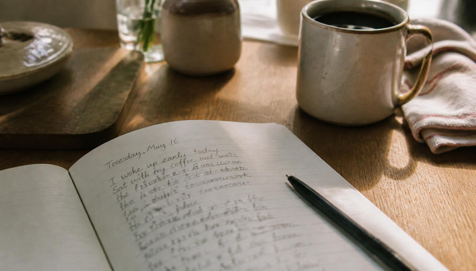 An open notebook and pen on a table in early morning light