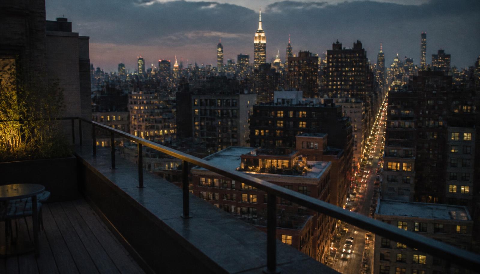 The railing of a Manhattan rooftop deck at dusk with the city below